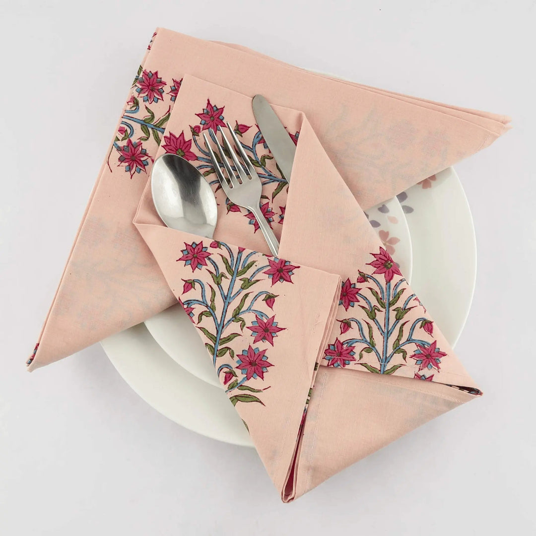 Folded floral-patterned napkin with cutlery on a white plate against a light background