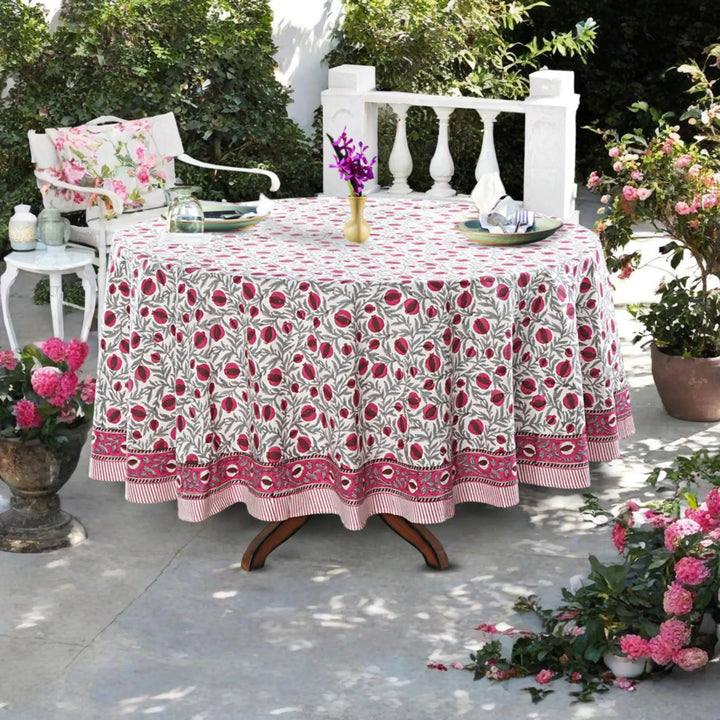 Outdoor table setting with a floral tablecloth, chairs, and decorative elements.