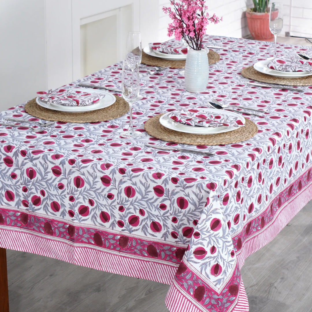 Dining table set with a floral patterned tablecloth in a bright room.