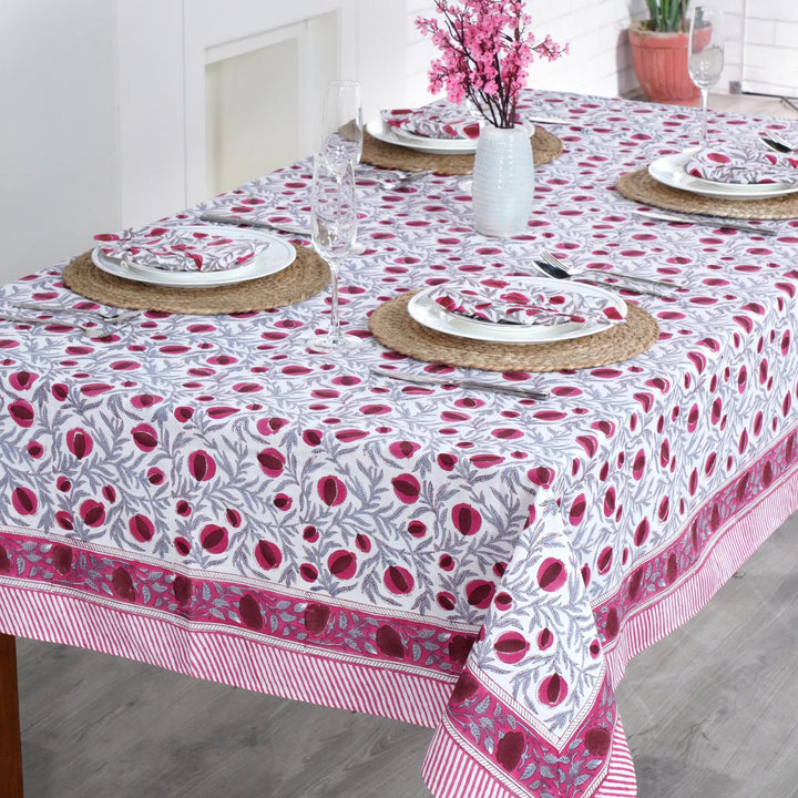 Dining table set with a floral patterned tablecloth in a bright room.