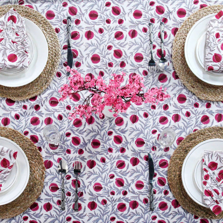 Table setting with a floral tablecloth and pink cherry blossom centerpieces.