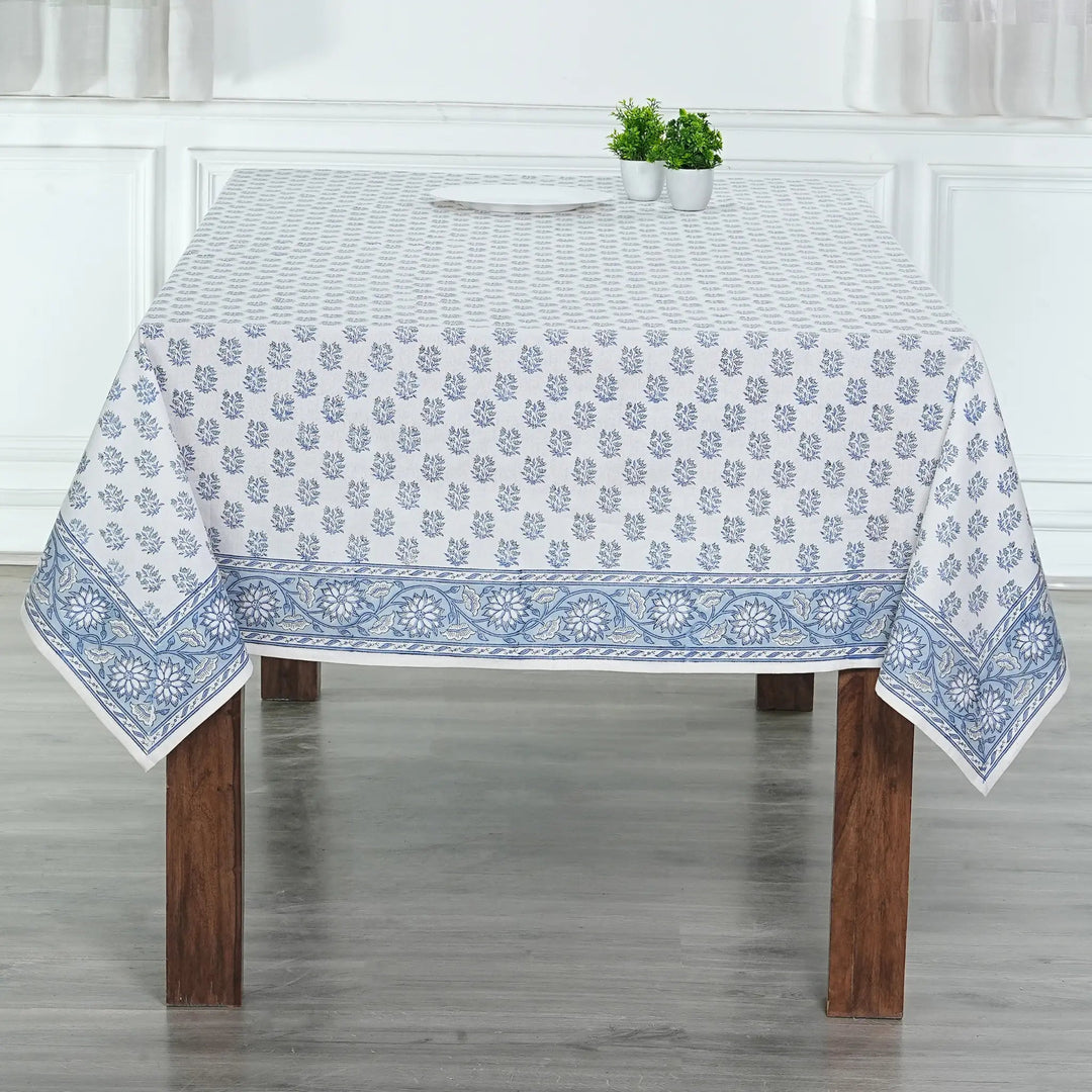 Tablecloth with blue floral pattern on a wooden table in a room with white walls.