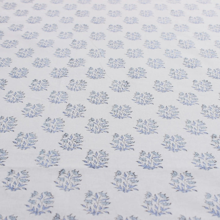 Patterned fabric with small blue floral designs on a light blue background