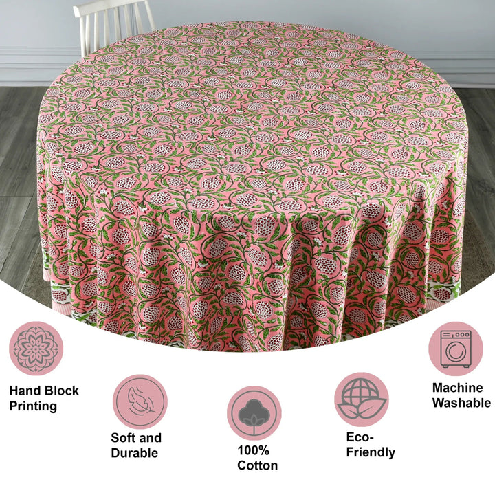 Round tablecloth with pink and green floral pattern on a wooden floor.