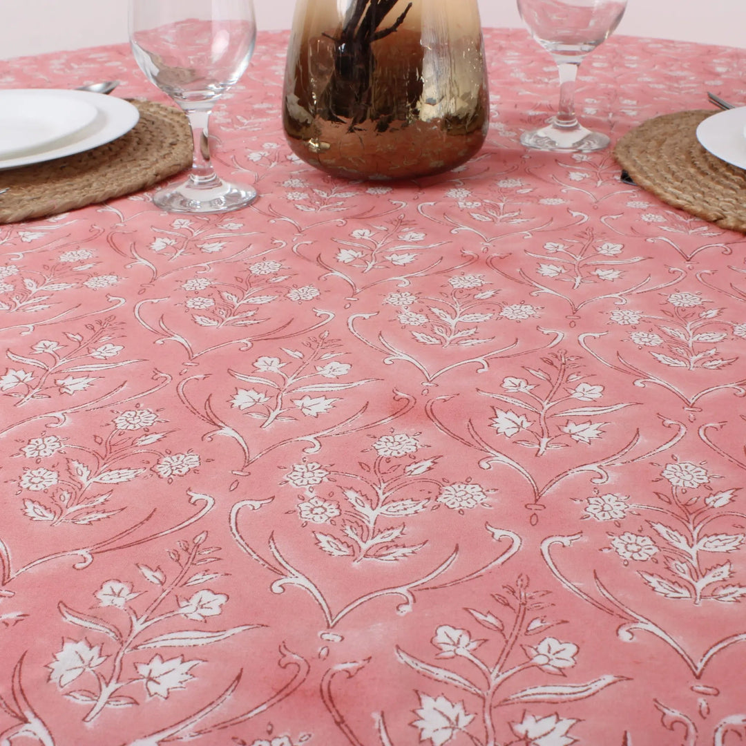 Pink tablecloth with white floral pattern on a set dining table.