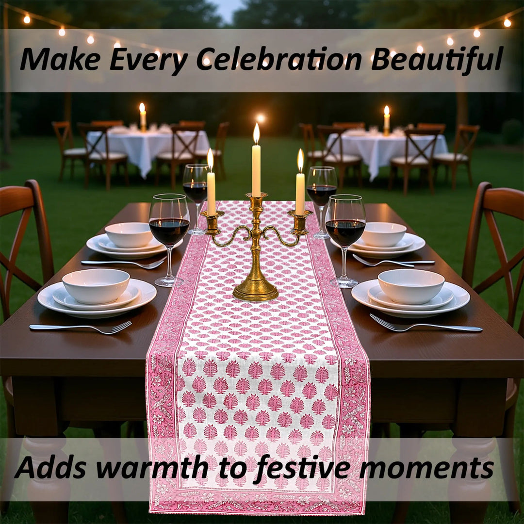 Dining table set with a pink floral table runner, candles, and wine glasses outdoors.