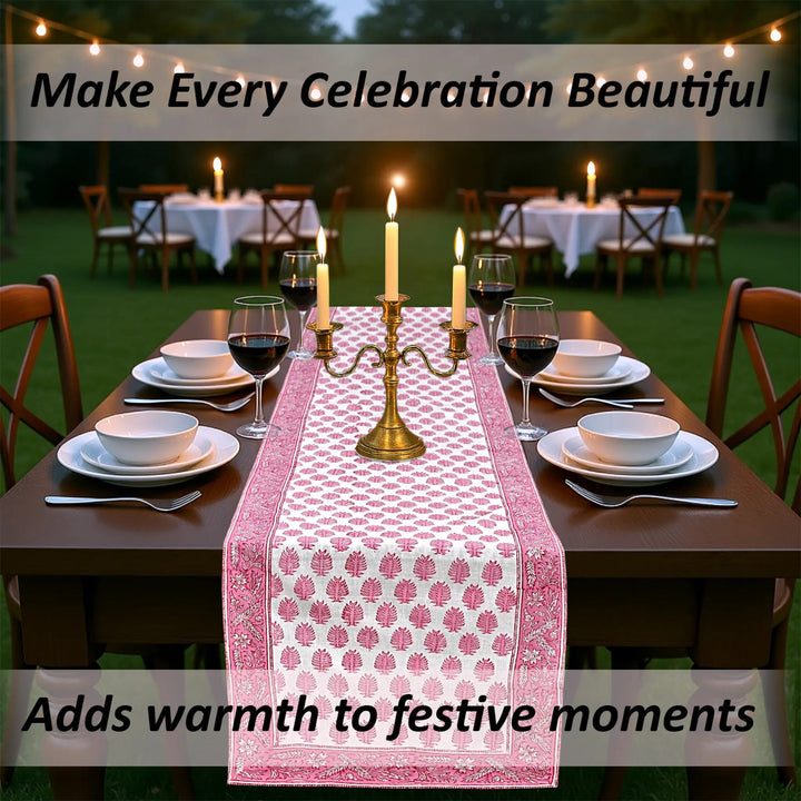 Dining table set with a pink floral table runner, candles, and wine glasses outdoors.