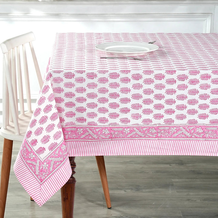 Tablecloth with pink leaf pattern on a wooden table and chair.