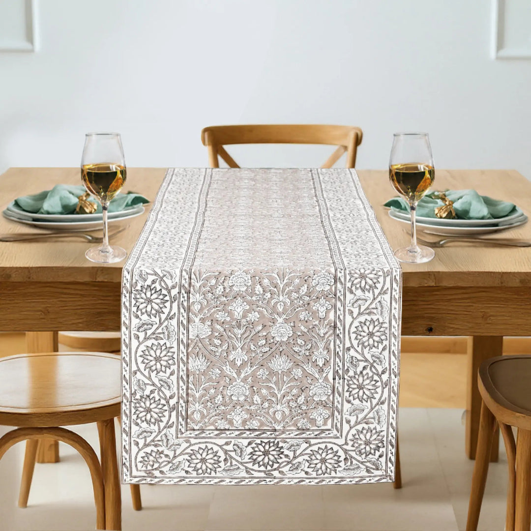 Dining table set with a patterned table runner, glasses, and plates.