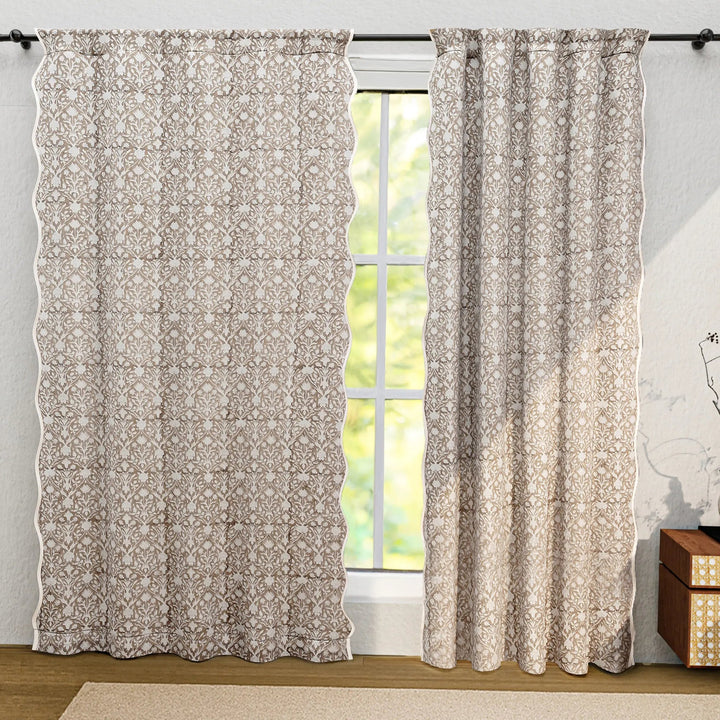 Floral patterned curtains hanging in front of a window with a light gray wall and wooden floor.