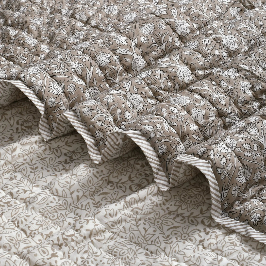 Floral patterned quilt with ruffled edges on a matching fabric background