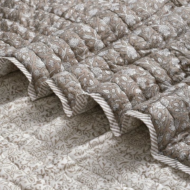 Floral patterned quilt with ruffled edges on a matching fabric background