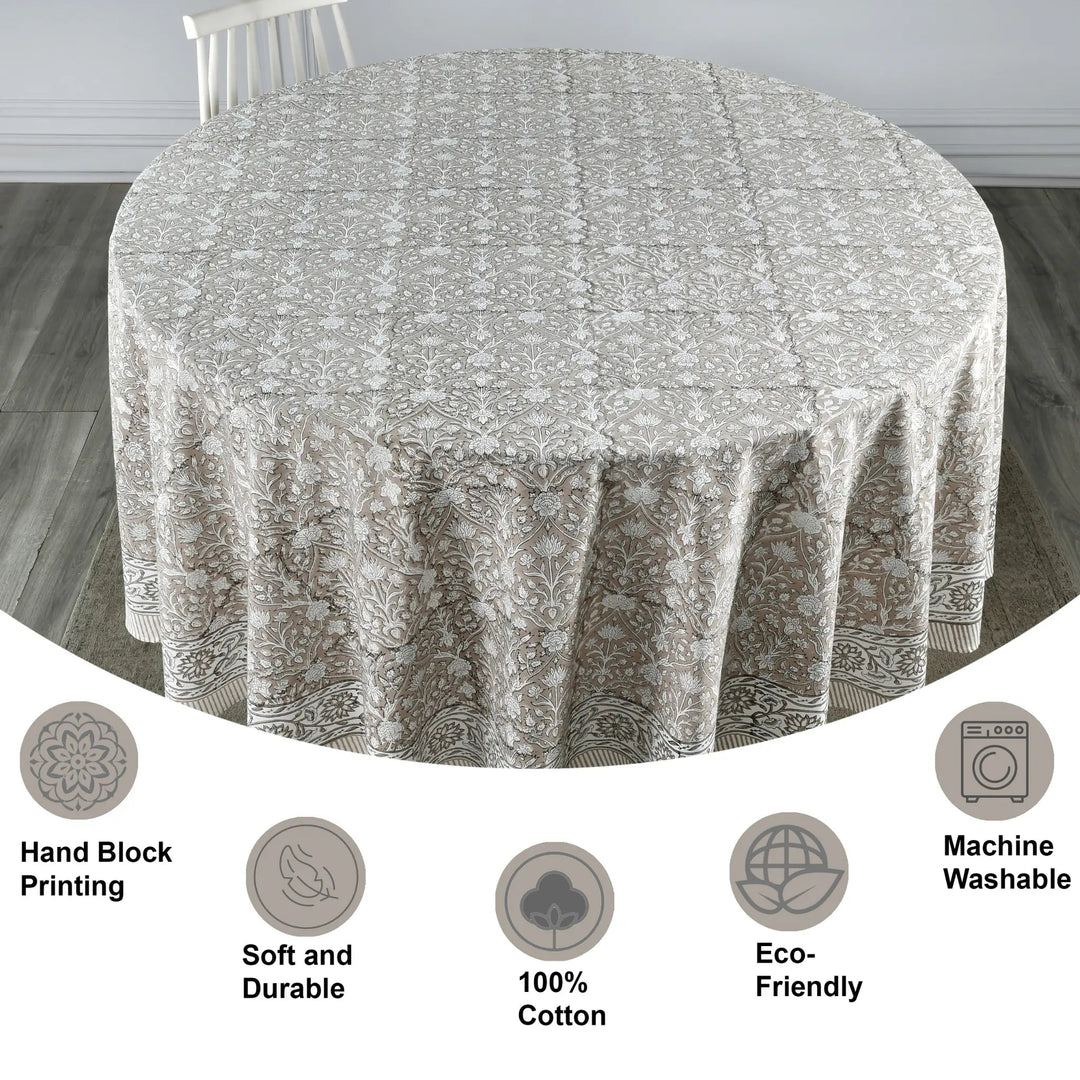 Round tablecloth with floral pattern on a wooden floor, featuring icons and text about material and care.