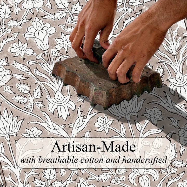 Hand using a wooden block to print a floral pattern on fabric with &