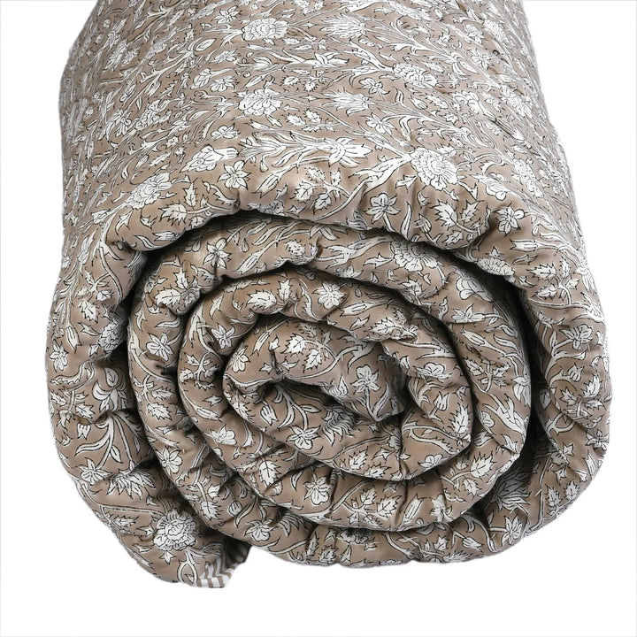 Rolled-up floral-patterned quilt on a white background