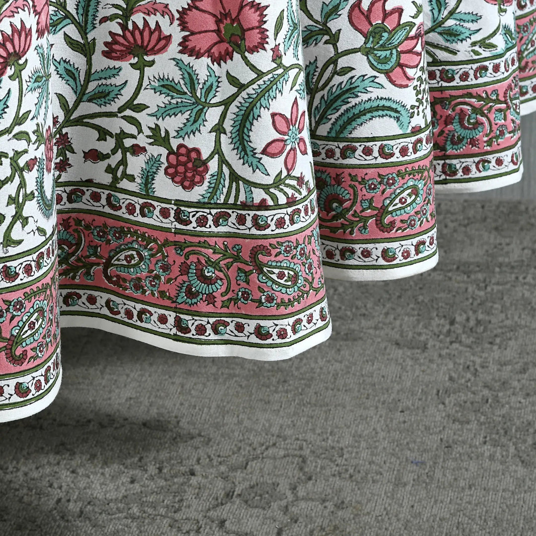 Close-up of a floral patterned fabric with pink, green, and red colors on a gray surface.