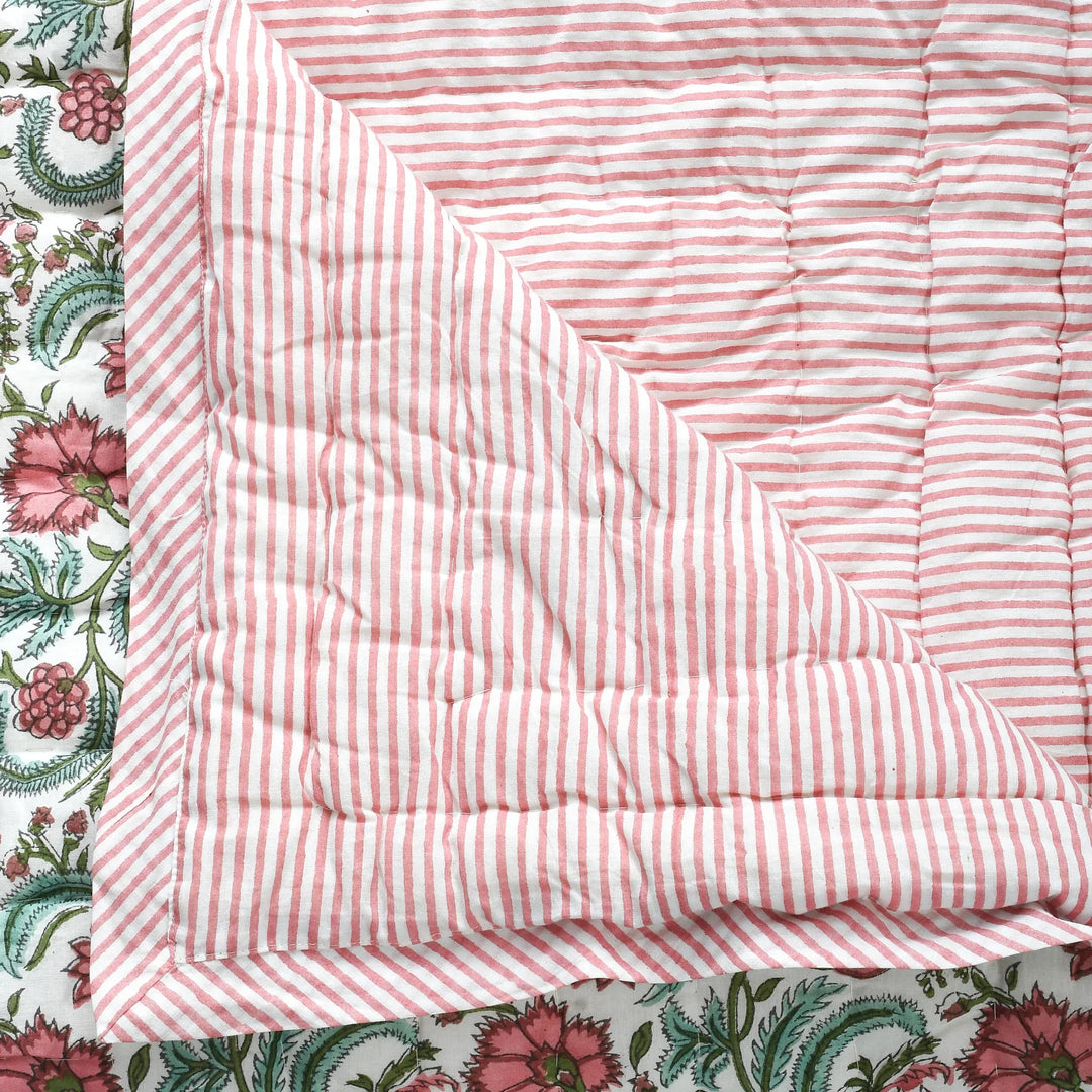 Pink and white striped quilt on a floral fabric background