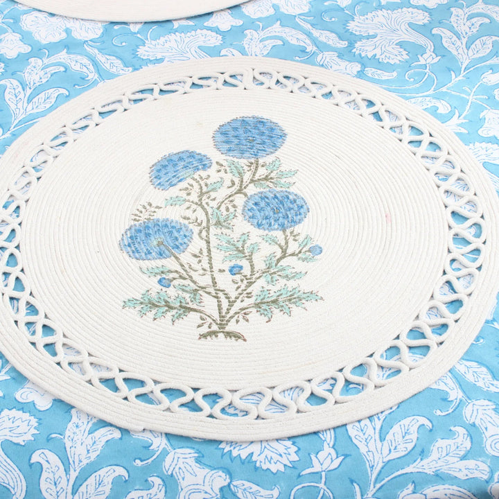 Decorative white placemat with floral design on a blue floral patterned background