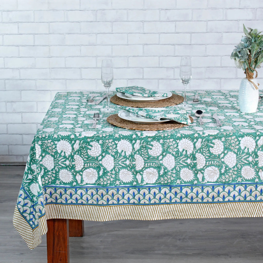 Tablecloth with floral pattern on a wooden table against a white brick wall.