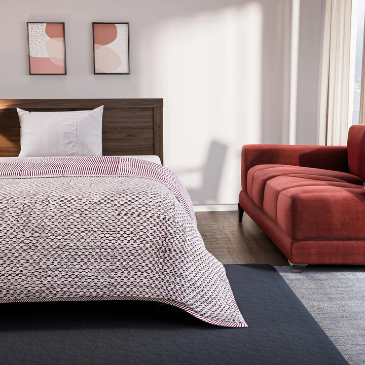 Bedroom with a bed covered in a patterned comforter and a red sofa.
