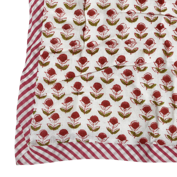 Floral patterned fabric with red and green flowers on a white background, bordered by red and white striped fabric.