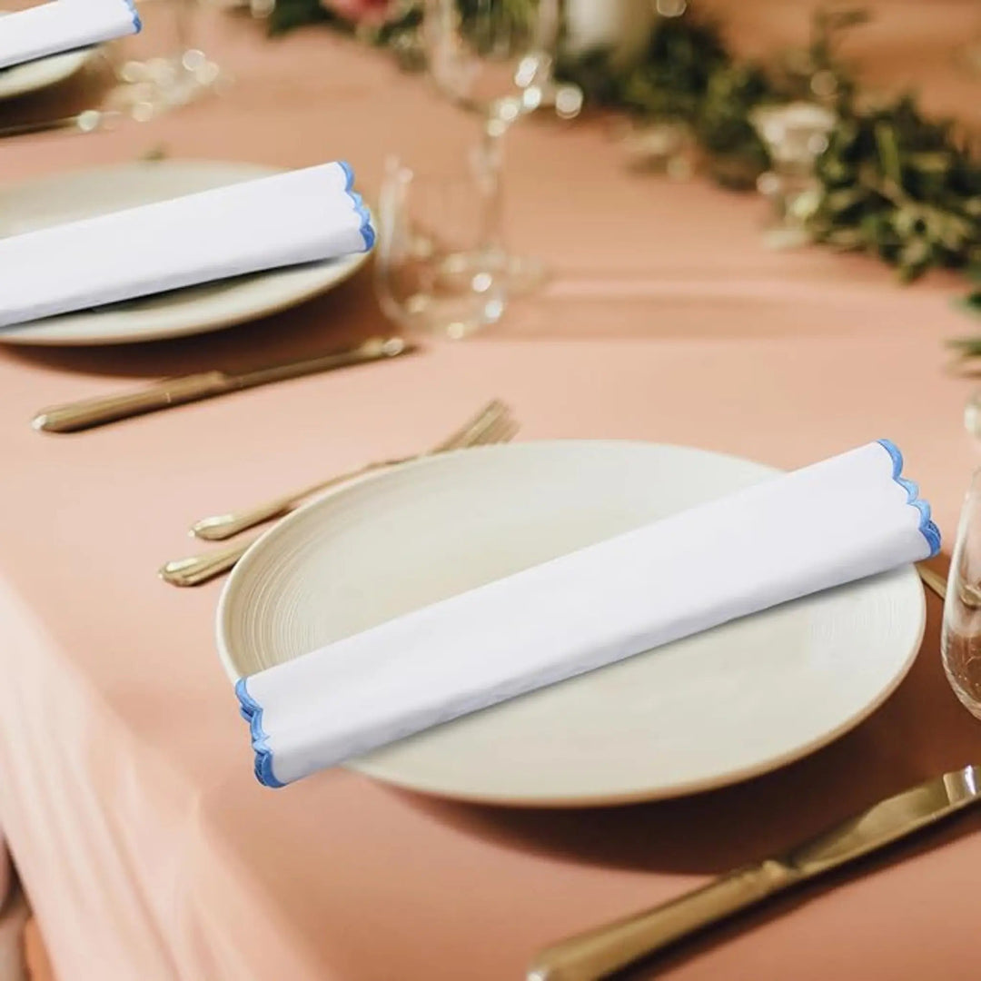 Table setting with plates, cutlery, and folded napkins on a pink tablecloth.