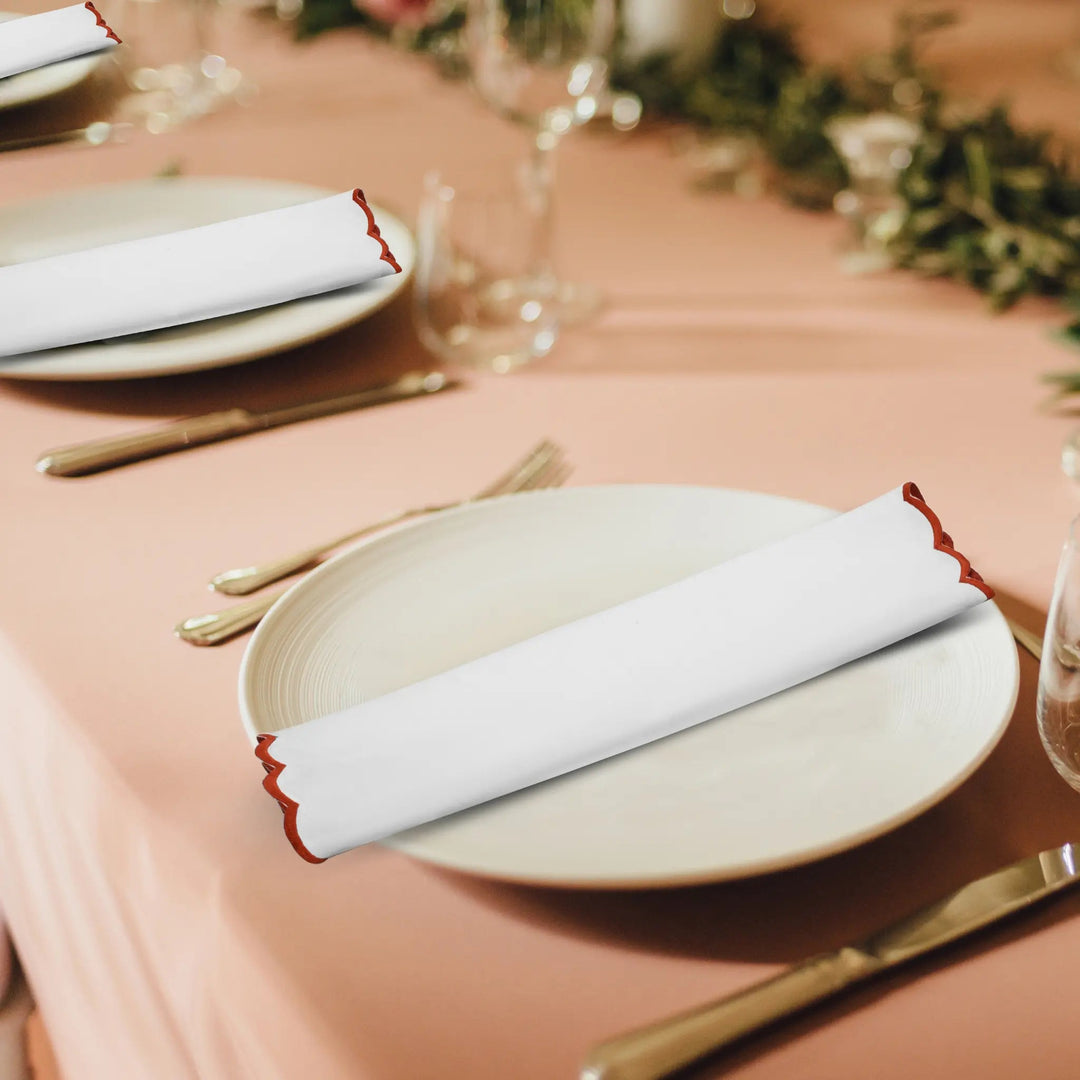 Dining table setting with plates, napkins, and cutlery on a pink tablecloth.