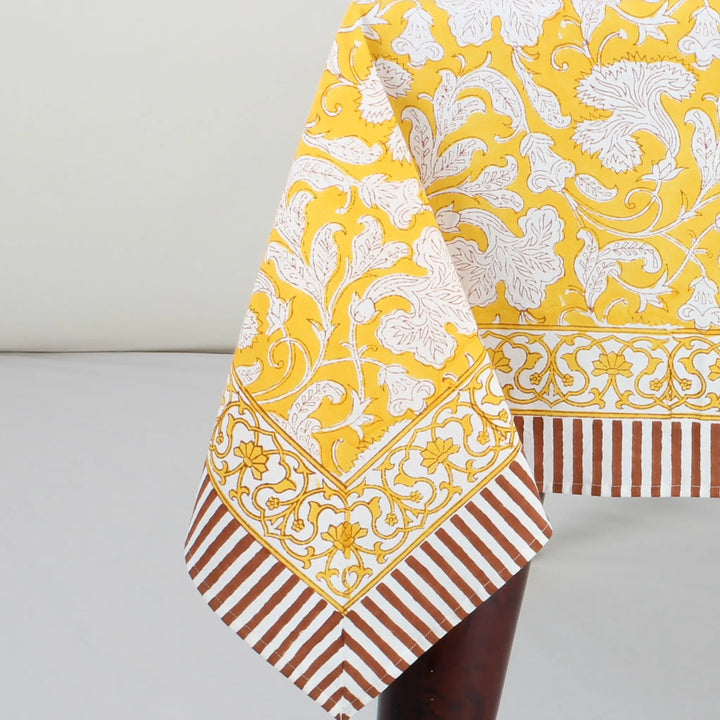 Yellow and white patterned fabric with brown and white striped fabric on a gray background